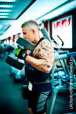 Фото мужчины с татуировкой на бицепсе во время силового упражнения