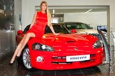 Фото красивой девушки модели, сидящей на красном купе кабриолете Dodge Viper