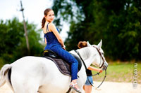 Фото уезжающей на белой лошади девушки, оборачивающейся назад, к зрителю