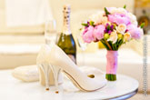 Свадебный натюрморт: белые туфли невесты, вдали - шампанское и букет