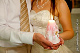 Фото горящей свадебной свечи семейного очага в руках жениха и невесты