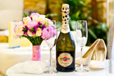 Фото бутылки Мартини с бокалами на столе, рядом - букет и туфли невесты