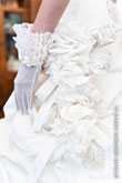 Фото фрагмент кружевных украшений на свадебном платье невесты и руки невесты в белой перчатке