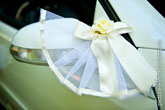 Фото белого банта с розой на боковом зеркале заднего вида свадебного автомобиля