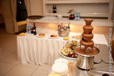 Фото шоколадной пирамиды, фруктов, шампанское и бокалы - в расфокусе
