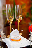 Свадебный фото натюрморт: золотые обручальные кольца в коробочке в форме сердца, вдали - бокалы для шампанского